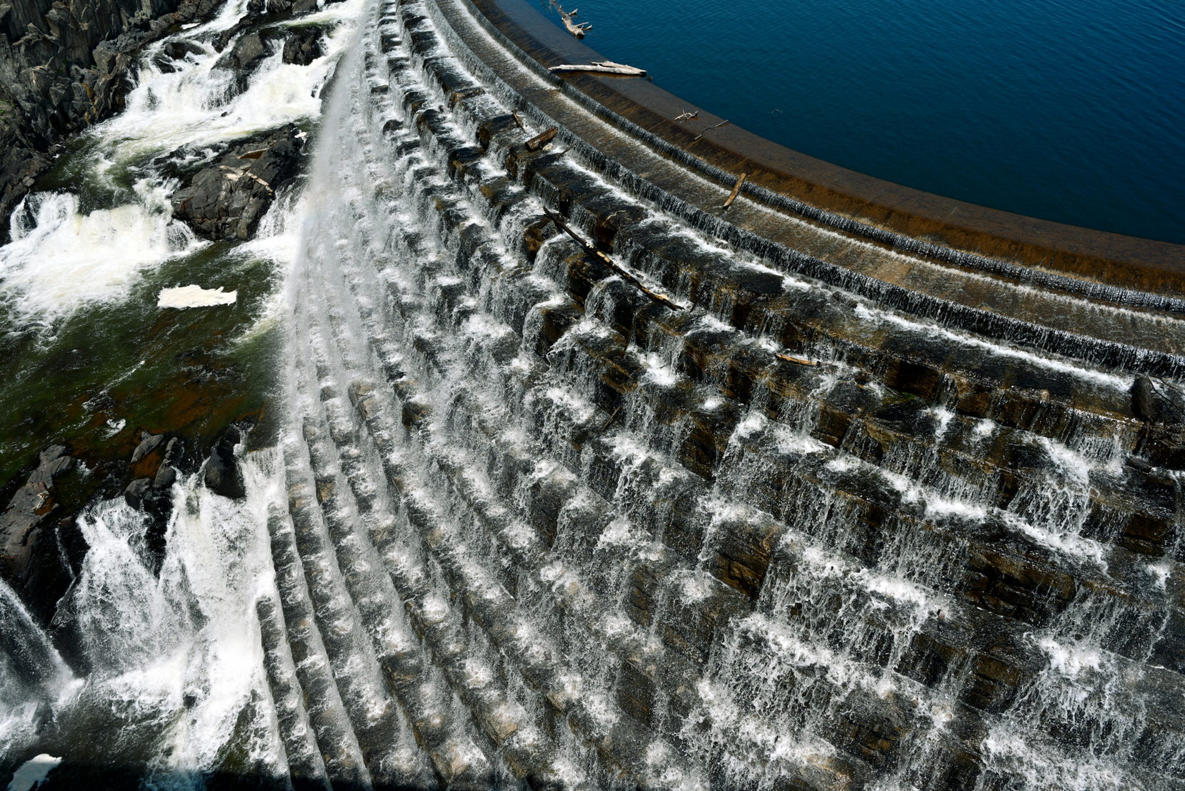 Water sheeting over the crest of a low weir across the full width of a river channel